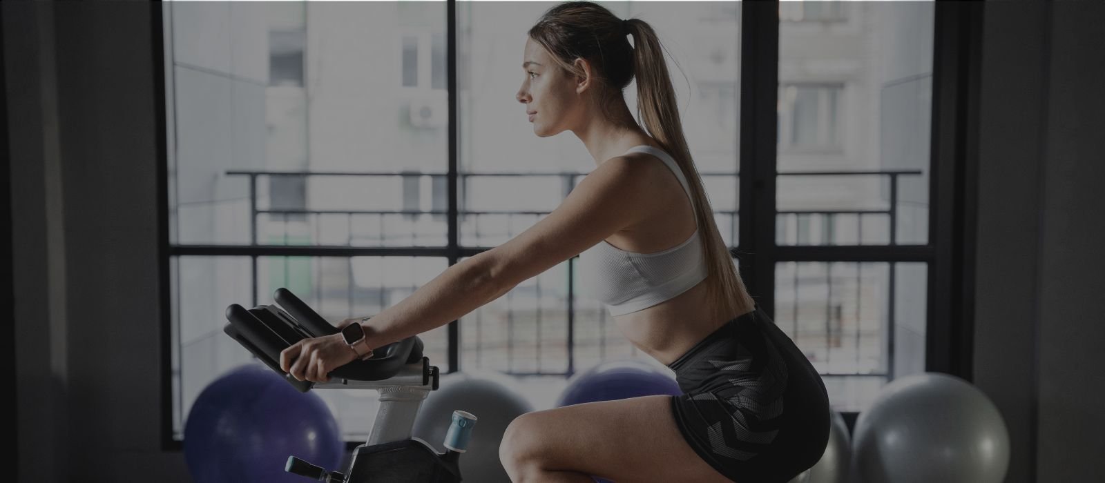 Moteris sportuojanti su dviračiu treniruokliu namuose